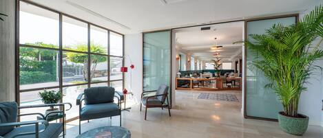 A spacious hotel lobby with a dining area, large windows, and a potted plant.