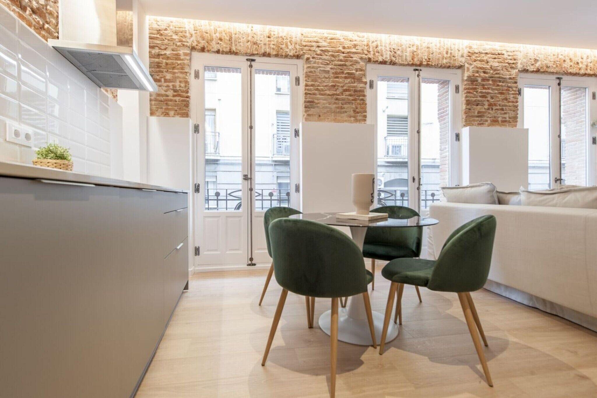 Una cocina moderna con comedor, armarios blancos y una pared de ladrillo decorativa.