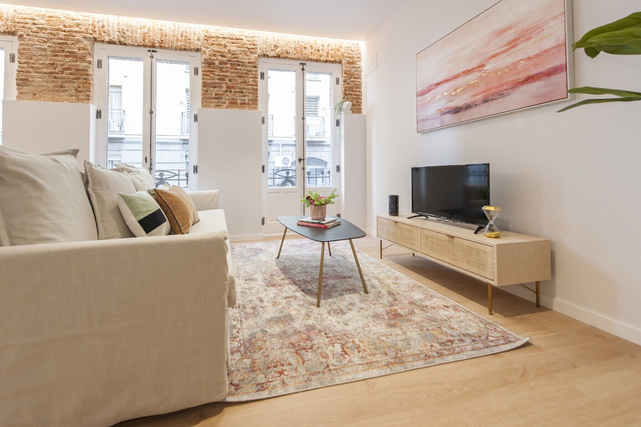 A living room with a sofa, a coffee table, a TV, and a plant.