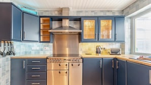 Una cocina moderna con armarios azules, electrodomésticos de acero inoxidable y un ventanal que proporciona luz natural.