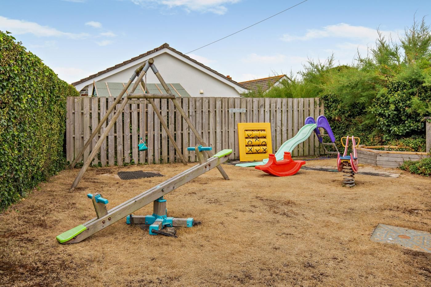 Ein Spielplatz mit Wippe, Rutsche und Schaukel.