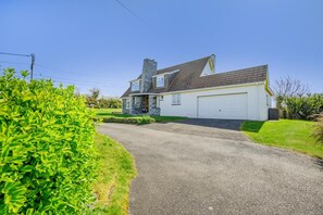 A two-story house with a garage, a driveway, and a well-maintained lawn. - 4 Bed in Harlyn Bay (oc-t35030) (Harlyn Bay)