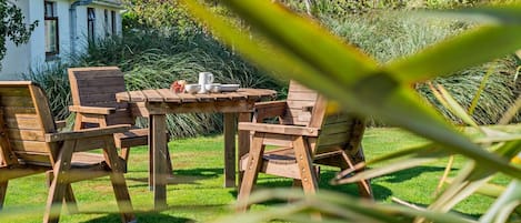 Ein Holztisch mit Stühlen und einer kleinen Tischdekoration in einem Garten.