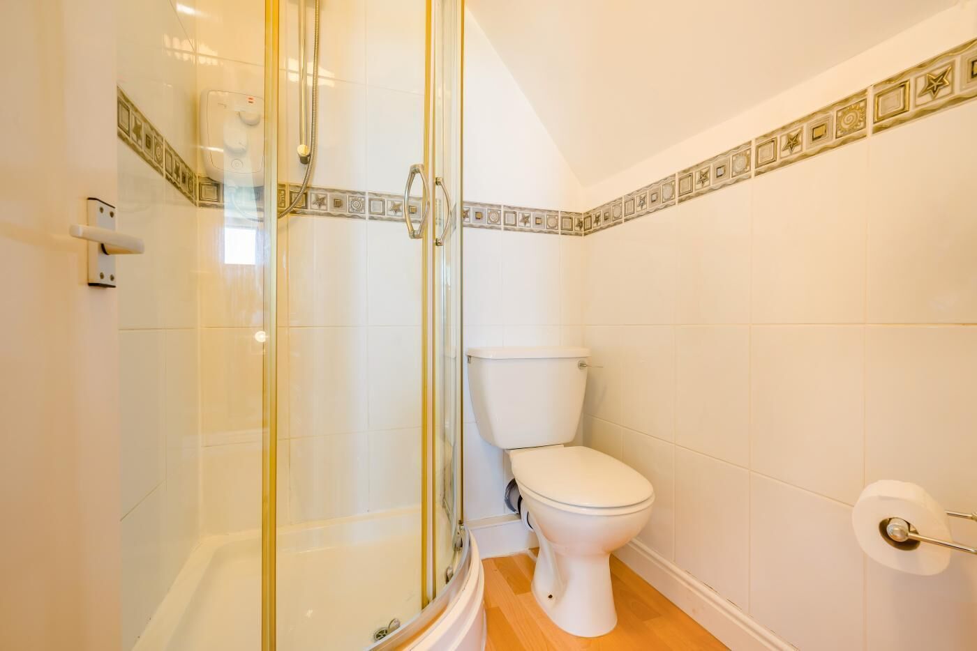 Een badkamer met een glazen douchecabine, een toilet en een betegelde vloer.