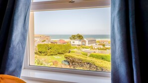Ein Fenster mit Blick auf eine Küstenwohngegend, mit Häusern und einem Strand.