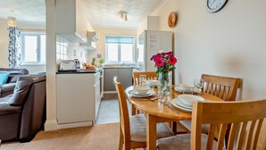 Ett kompakt bostadsutrymme med en matplats, ett litet kök och en soffa.