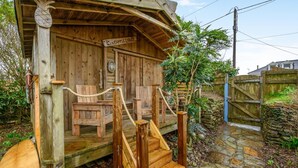 Een houten lodge met een bord waarop 'Pineapple Lodge' staat, een houten trap en een rustieke buiten zitplaats.