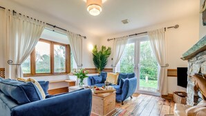 Een gezellige woonkamer met een blauwe zithoek, een houten salontafel en een open haard.