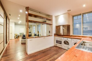 Eine moderne Küche mit Holzarbeitsplatte, integrierten Geräten und einem großen Fenster.
