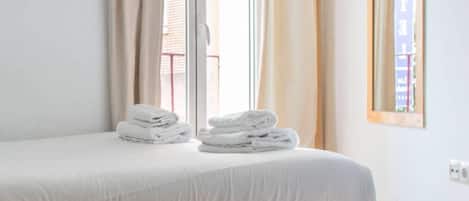 Une chambre d’hôtel avec un lit, une fenêtre avec des rideaux et un panneau fixé au mur.