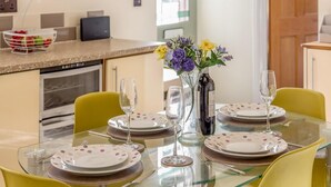 Een eetgedeelte met een glazen tafel, gedekt voor vier personen, omringd door gele stoelen.