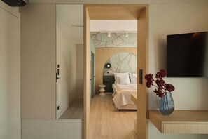 A bedroom with a bed, bedside table, and a TV mounted on the wall. - Persante Sunrise Collection 6 | Riverview | AC (Kołobrzeg)