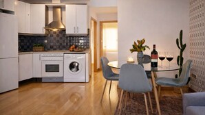 Una cocina compacta con electrodomésticos modernos, una zona de comedor con mesa de cristal y una decoración de cactus.