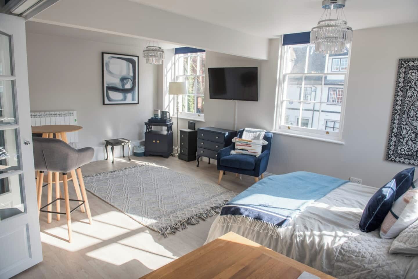 Une chambre à coucher avec un lit, un bureau, une chaise, une commode, une télévision et une fenêtre.