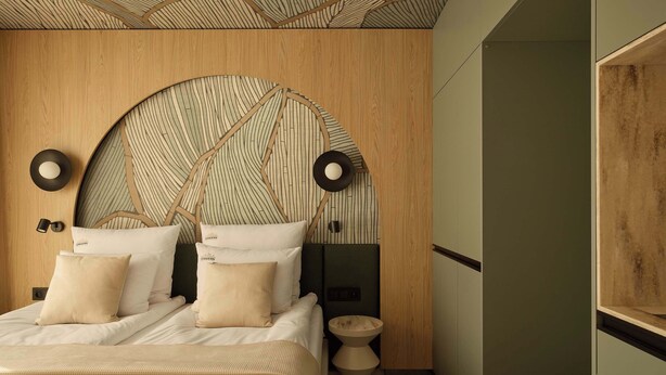Un dormitorio moderno con cabecera de madera, un espejo redondo y una mesita de noche.