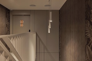 Ein modernes Interieur mit Treppe, eingelassener Beleuchtung und einer Wand mit einem Nummernschild.