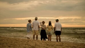 Um grupo de pessoas em uma praia, com o oceano ao fundo.