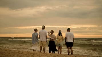 A group of people standing on a beach with the ocean in the background.