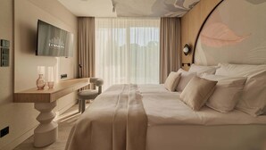 Quarto de hotel com cama, televisão, escrivaninha e cadeira.
