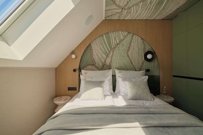 A bedroom with a skylight, a curved headboard, a bedside table, and a nightstand. - Persante Sunrise Collection 5 | Riverside | AC (Kołobrzeg)