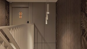En modern inredning med en trappa, en väggmonterad lampa och en dörr med ett nummerskylt.