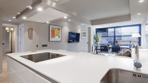 A modern kitchen with a central island, recessed ceiling lights, and a dining area with a table and chairs. - 6-Guest Haven near Golden Mile (Madrid)
