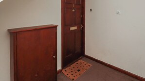 A wooden door with a handle, a small rug with star patterns, and a light switch on the wall. - Flodden Apartment (Wooler)