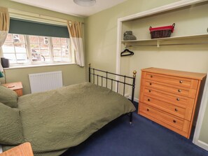 Ein Schlafzimmer mit Bett, Schminktisch und einem Fenster mit Vorhängen.