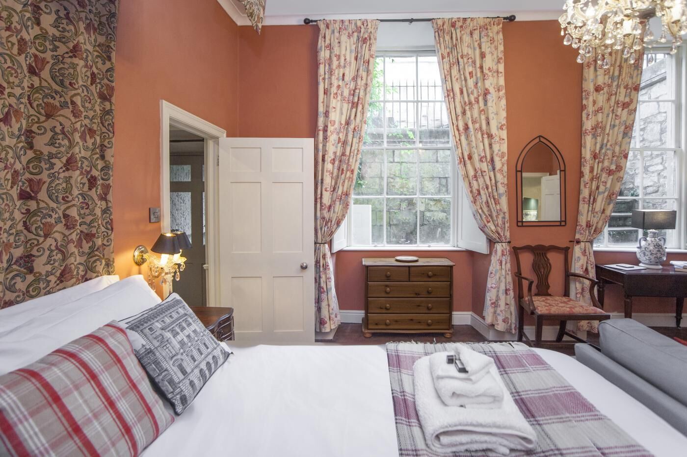 A bedroom with a bed, a dresser, a chair, a desk, and a window with curtains.