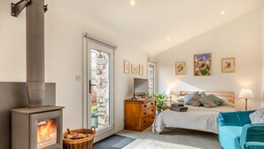 Ein Schlafzimmer mit Kaminofen, einem Bett, einer Kommode, einem Fernseher und Bildern an der Wand.