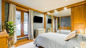 A bedroom with a large bed, a TV, a wardrobe, and a window with curtains. - 4 Bed in East Dean (oc-l34384) (East Dean)