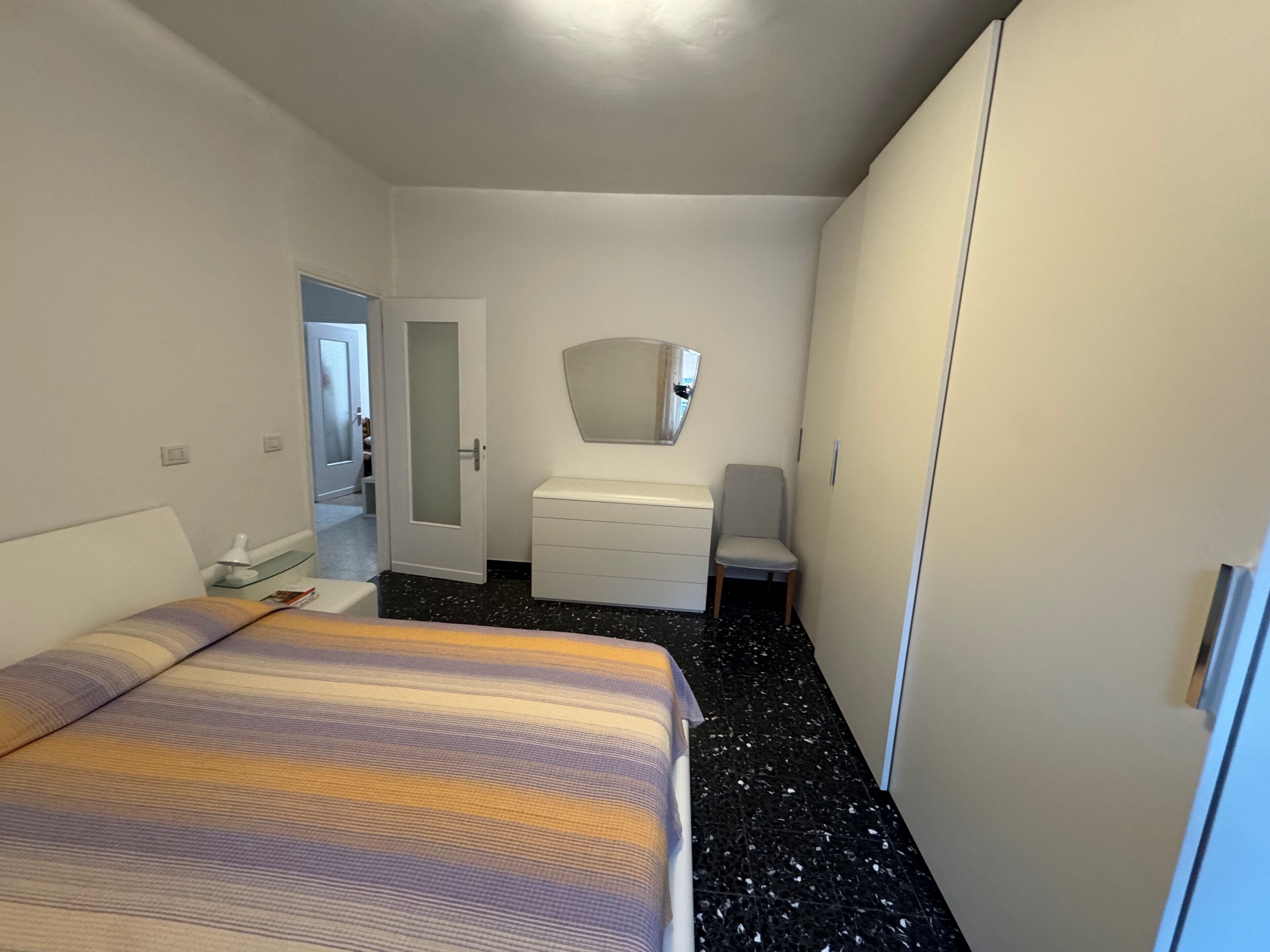 Une chambre à coucher comprenant un lit, une commode, une chaise et une porte donnant sur une autre pièce.