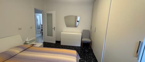 Une chambre à coucher comprenant un lit, une commode, une chaise et une porte donnant sur une autre pièce.