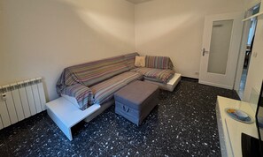 A small room with a sofa, a bench, a small table, and a radiator. - Calaqui in the centre near the beach (Monterosso al Mare)