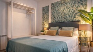 Ein Schlafzimmer mit einem Bett, einem Nachttisch, einer Lampe, einer Pflanze und einem Kleiderschrank.