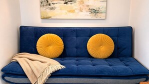 Un canapé bleu avec des coussins jaunes et un plaid beige.