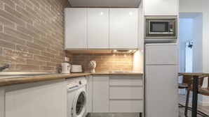 Une cuisine compacte équipée d’un lave-linge, d’un four à micro-ondes et d’un petit coin repas.