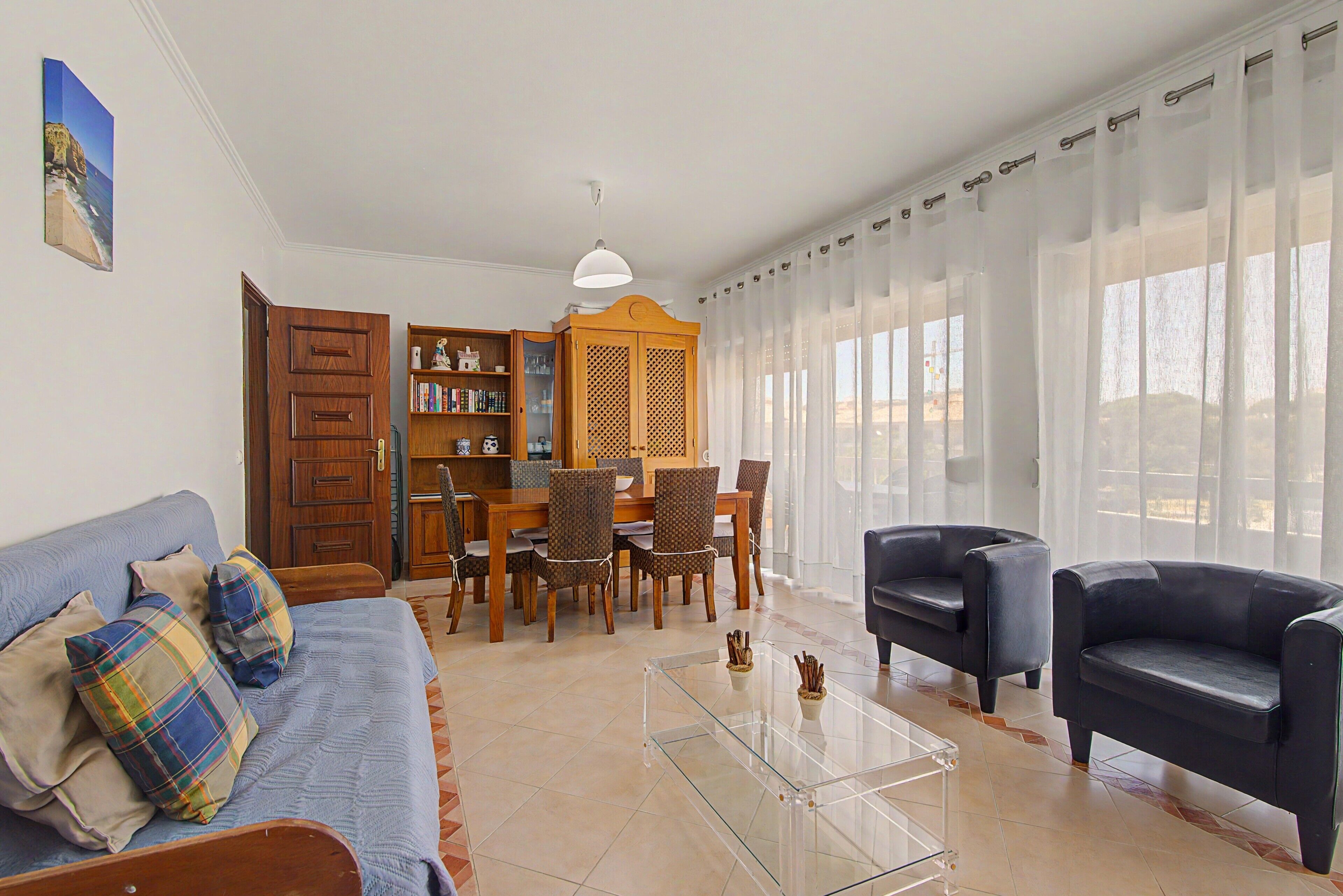 A living room with a sofa, chairs, a coffee table, and a dining area with a table and chairs.