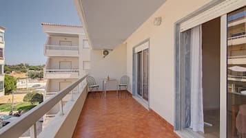 A balcony with a tiled floor, two chairs, a small table, and a potted plant.