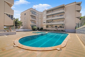 A swimming pool surrounded by a multi-story building with balconies. - Apartment 'Estrela Do Forte' with Shared Pool, Balcony and Wi-Fi (Quarteira)