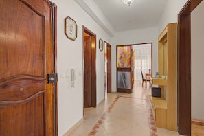 A hallway with wooden doors, a telephone, and a patterned rug. - Apartment 'Estrela Do Forte' with Shared Pool, Balcony and Wi-Fi (Quarteira)