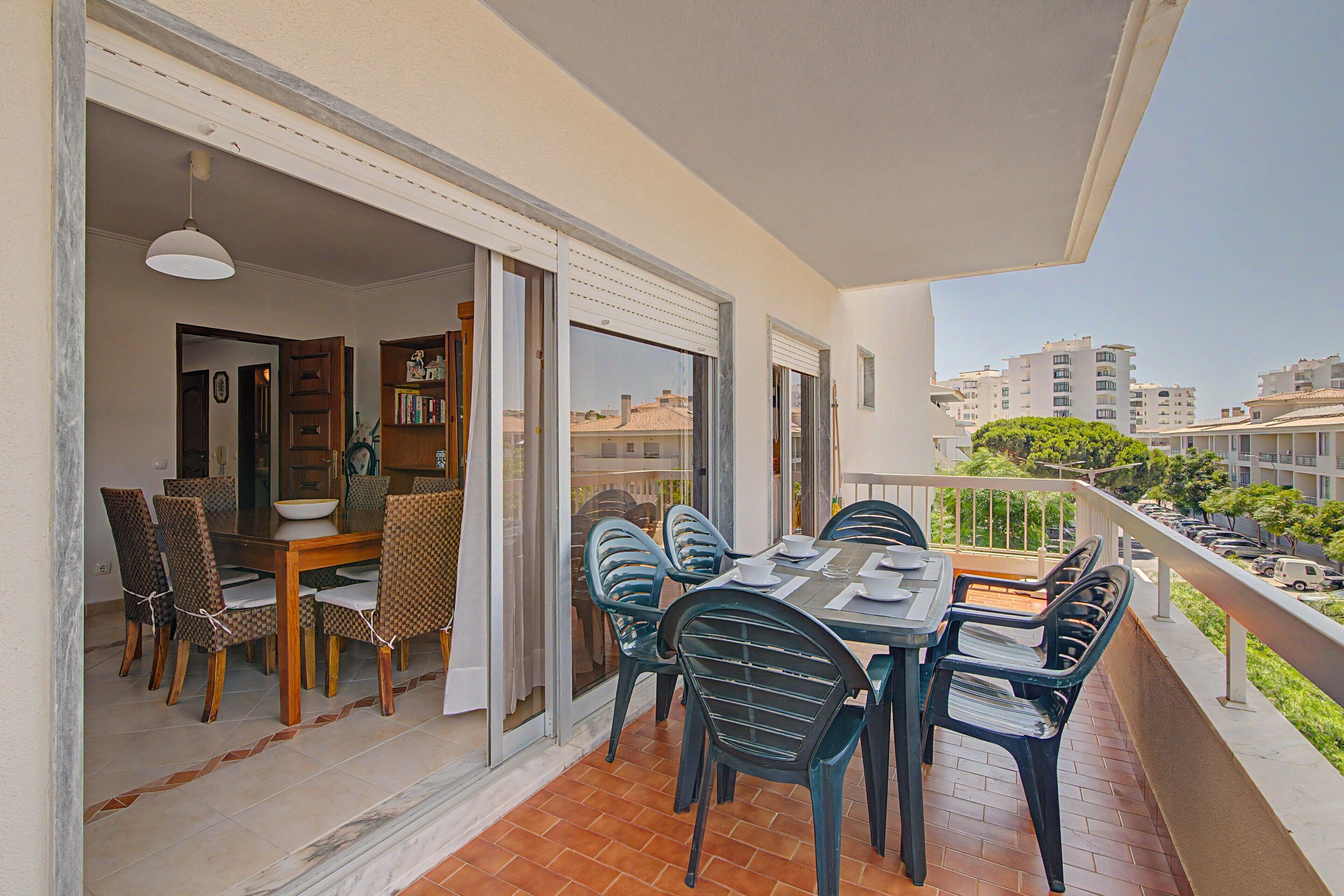 Un balcon avec une table et des chaises pour prendre les repas, une vue sur le paysage urbain et une porte donnant sur un espace intérieur doté d’une bibliothèque.