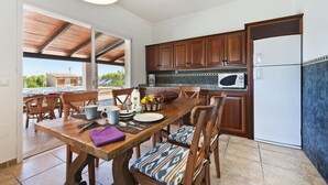 Una cocina con armarios de madera, un refrigerador y una mesa de comedor con sillas.
