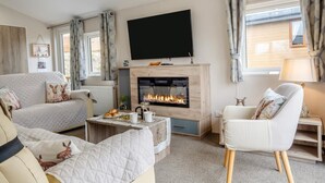 A living room with a fireplace, a flat-screen TV, a sofa, a coffee table, and a chair. - 2 Bed in Upton (oc-c35149) (Ryde)