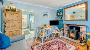Een woonkamer met een open haard, een televisie en een eethoek.