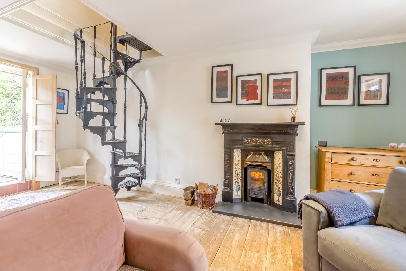 Un salon chaleureux avec une cheminée, un escalier en colimaçon et un plancher en bois.