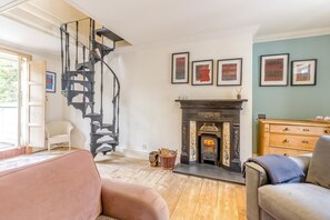 Una sala de estar acogedora con chimenea, una escalera en espiral y suelo de madera.