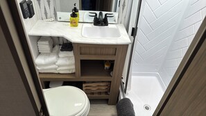 Een douche, handdoeken, zeep, toiletpapier