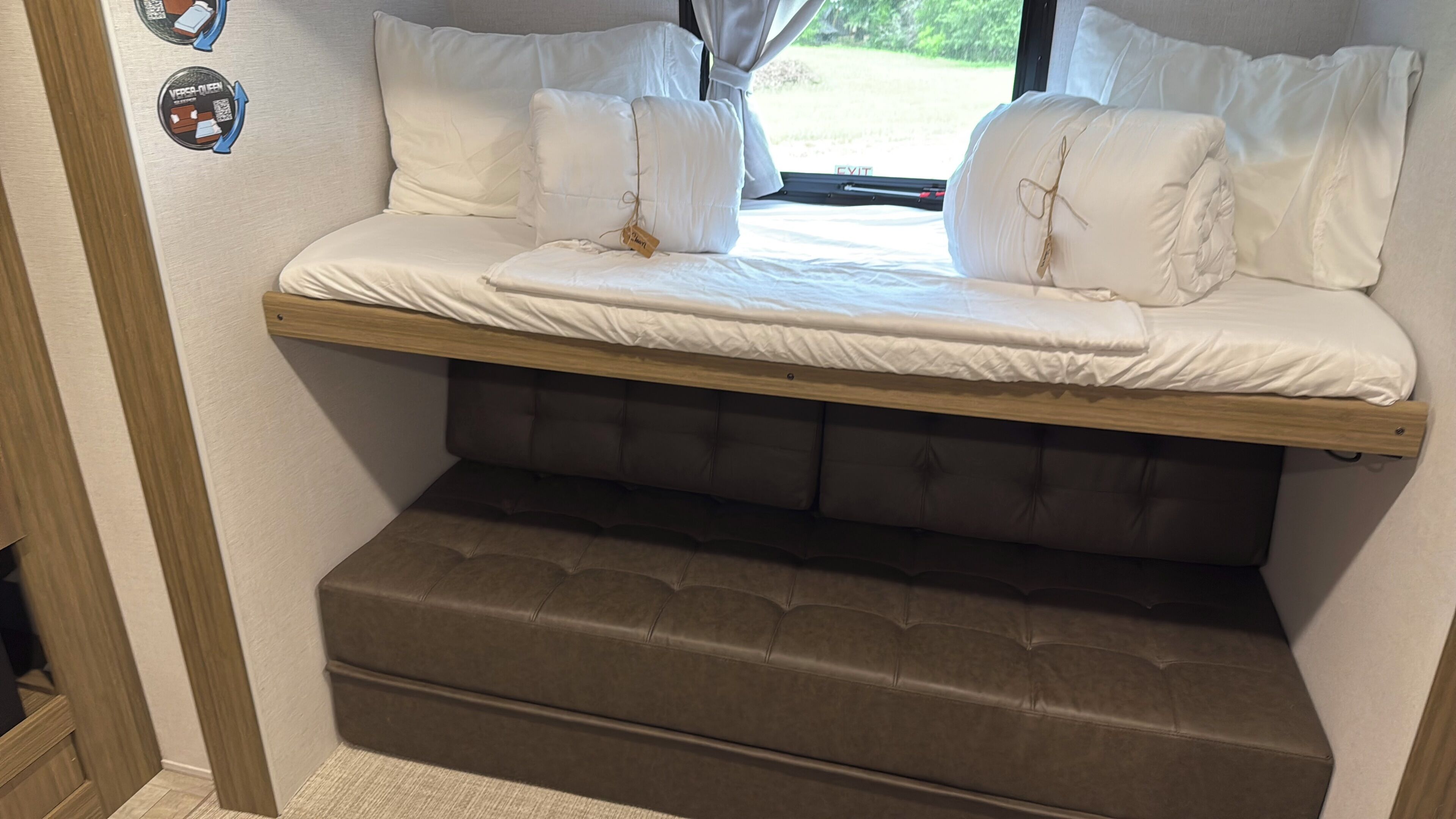 Una cama con cabecera, almohadas y una ventana con cortinas.