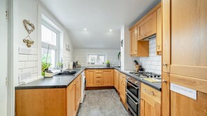 A modern kitchen with wooden cabinets, a black countertop, and a built-in oven. - 3 Bed in Castle Douglas (oc-c35143) (Castle Douglas)